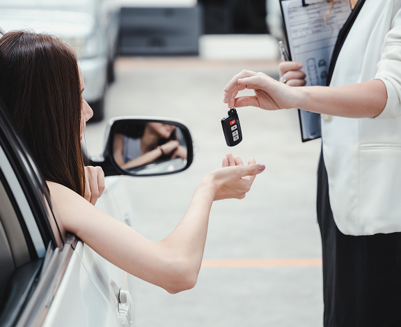 smilling woman getting key for her new car